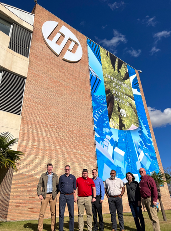 Team beside a large-format building wrap and logo installed on an HP office facade